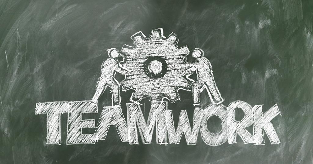 The image depicts two figures working together to push a gear labeled “TEAMWORK”, symbolizing the collective effort and synergy within Business Intelligence teams. The gear represents the dynamic role of OKRs as catalysts for collaboration and communication. Just like the figures working in unison to move the gear, OKRs align diverse skill sets and perspectives towards shared objectives, fostering cross-functional synergy.